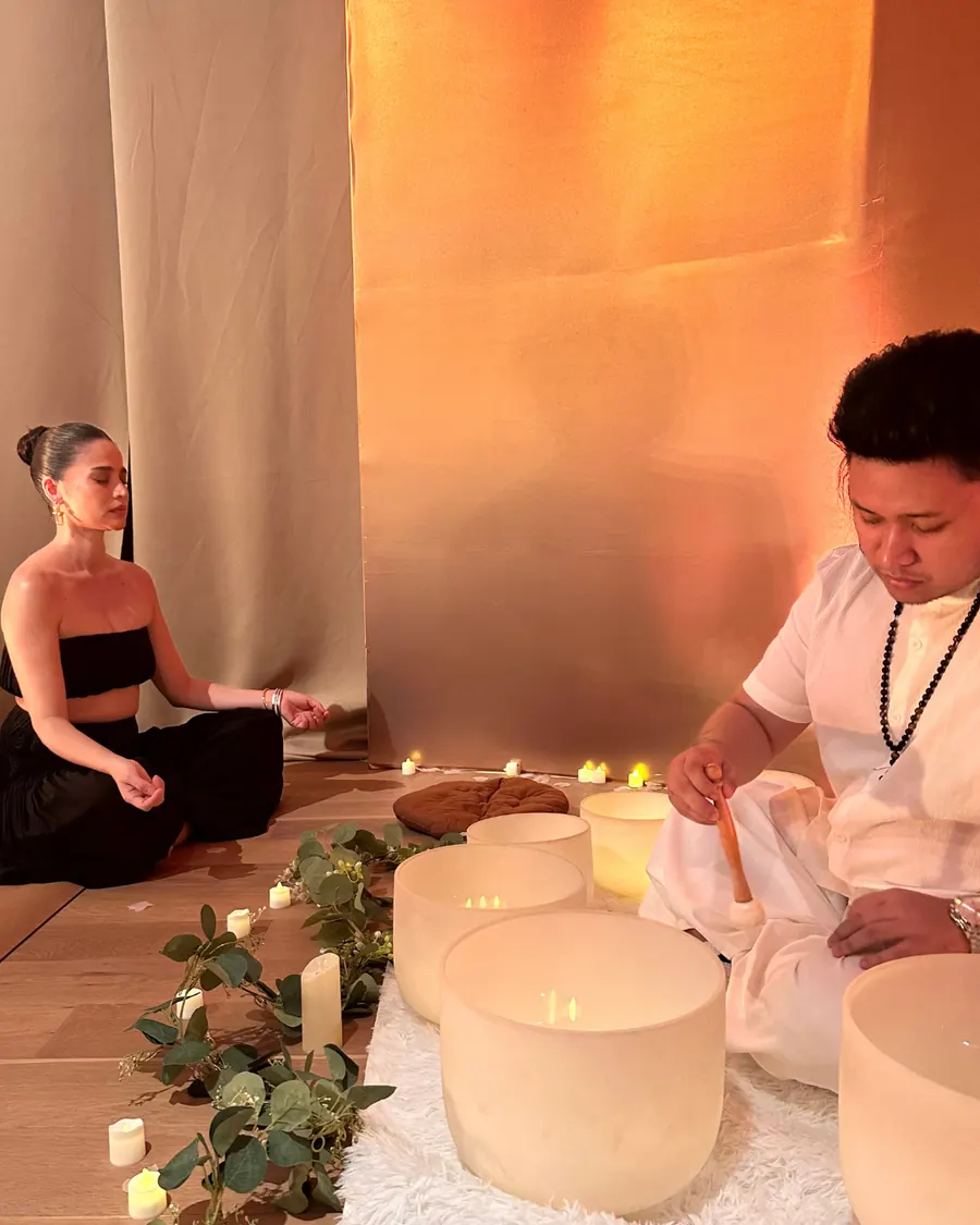 Anne Curtis seated in meditation during a candlelit Tallaro sound bowl session.