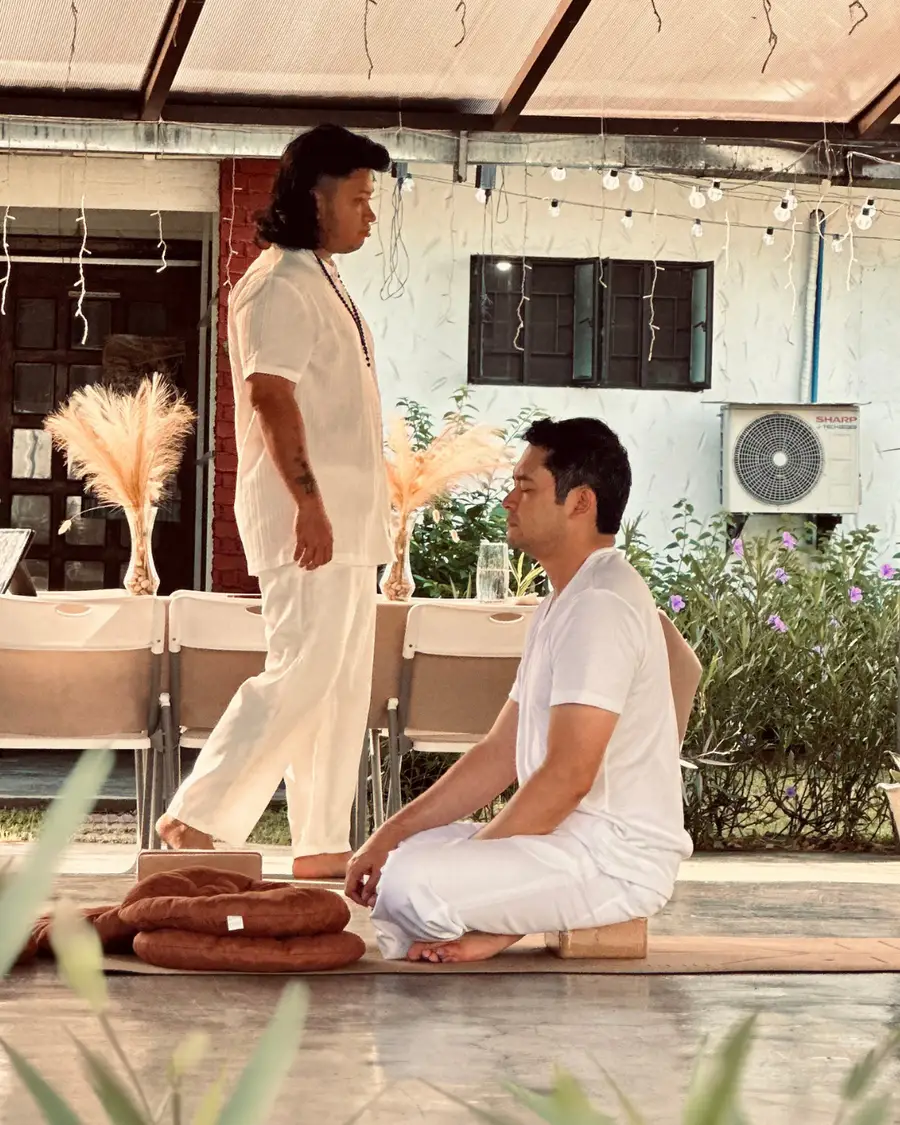 Jaime M. Singson seated in meditation on a mat during an outdoor Tallaro practice.