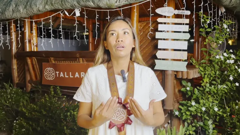 Nyla Burgos speaking to camera beneath the lantern-lit garden pavilion at the Tallaro Healing Center.